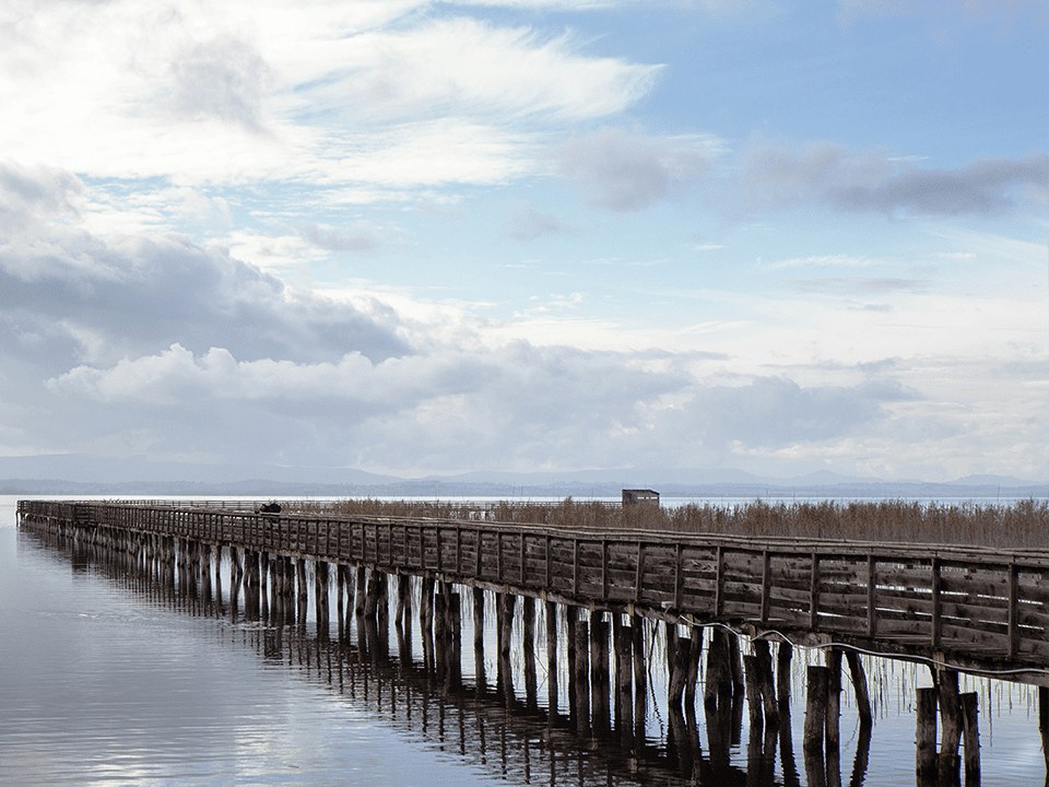 old-wooden-jetty-extending-out-into-sea-cloudy-sky